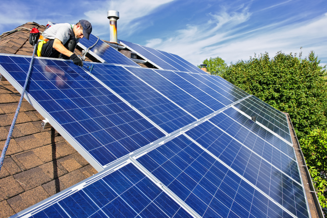 technician installing solar panels on roof