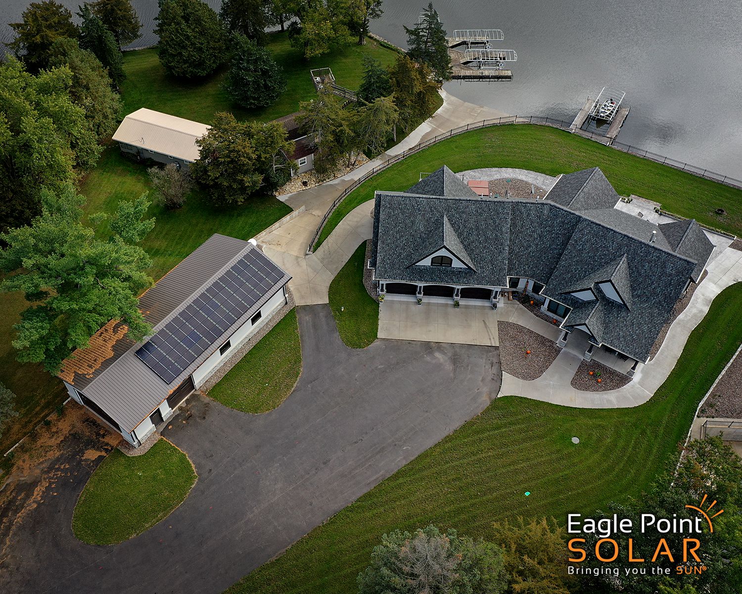 aerial view of residential house on a lake with solar panels on the garage
