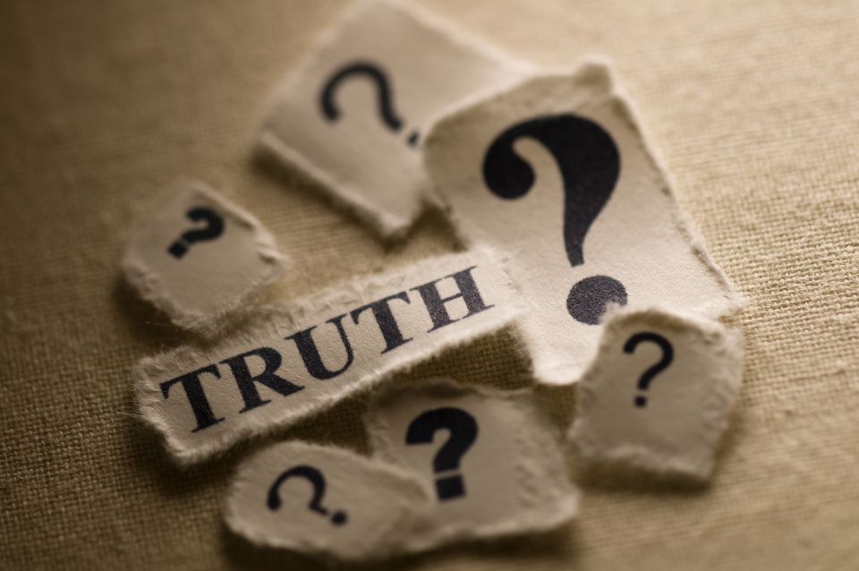 A photo with a slip of paper with the word truth surrounded by slips with question marks.